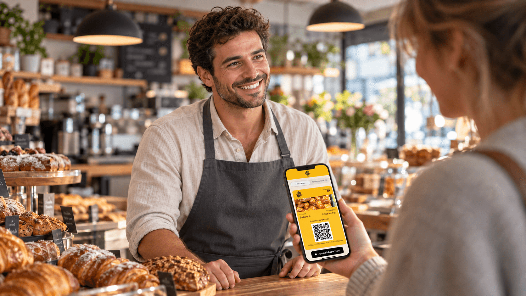 Une cliente présente sa carte de fidélité yakado sur son téléphone à un boulanger